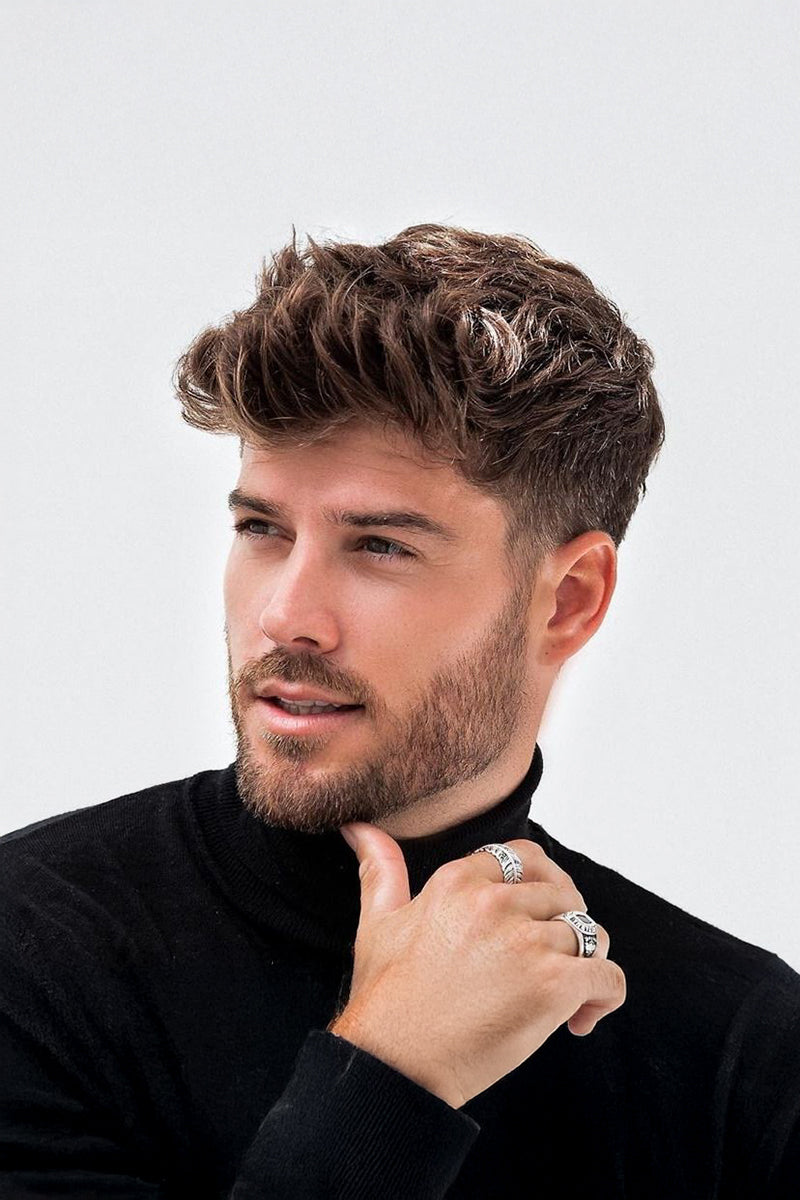 Man with styled hair and beard wearing a black turtleneck against a white background