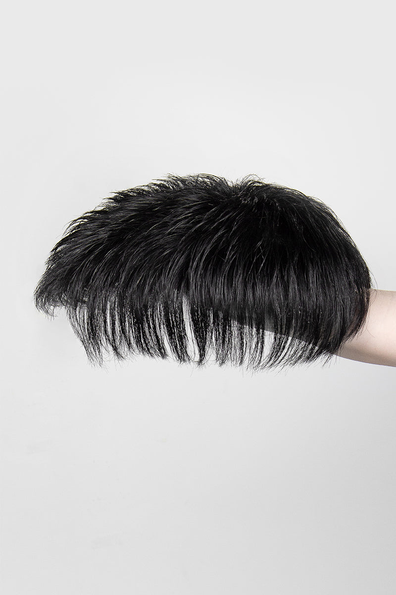 Black hairpiece held by a hand on a light gray background