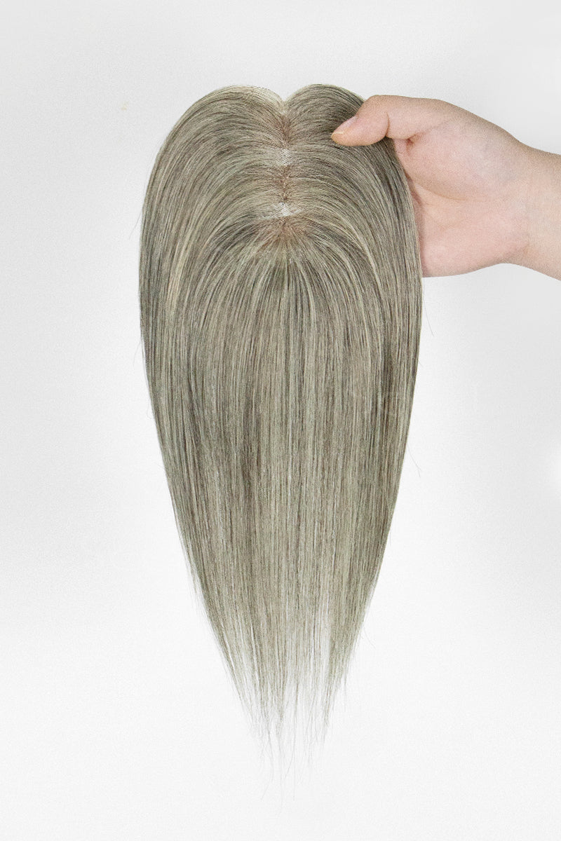 Hairpiece held by a hand against a white background