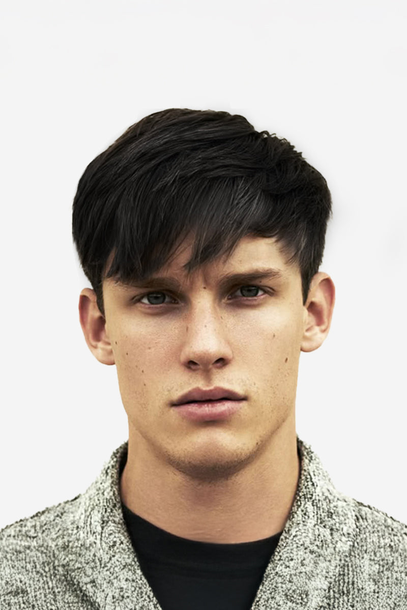 Man with stylish haircut wearing a textured jacket against a plain background