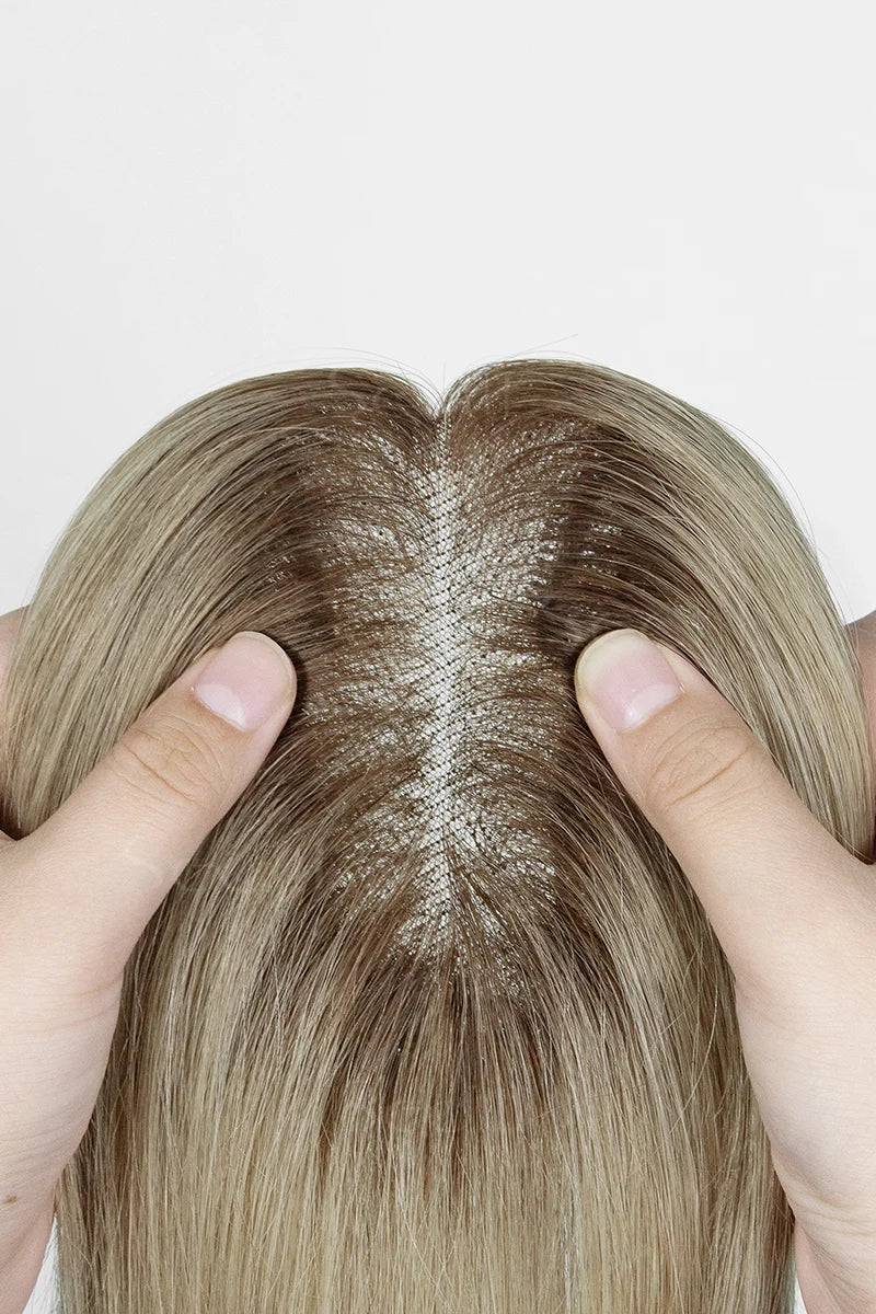 Close-up of a person's scalp with hands holding the sides, on a white background