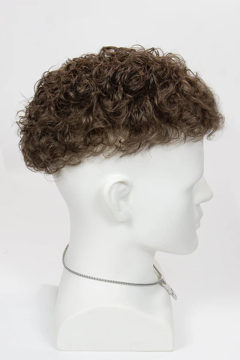 Man with styled hair and beard wearing a black turtleneck against a white background