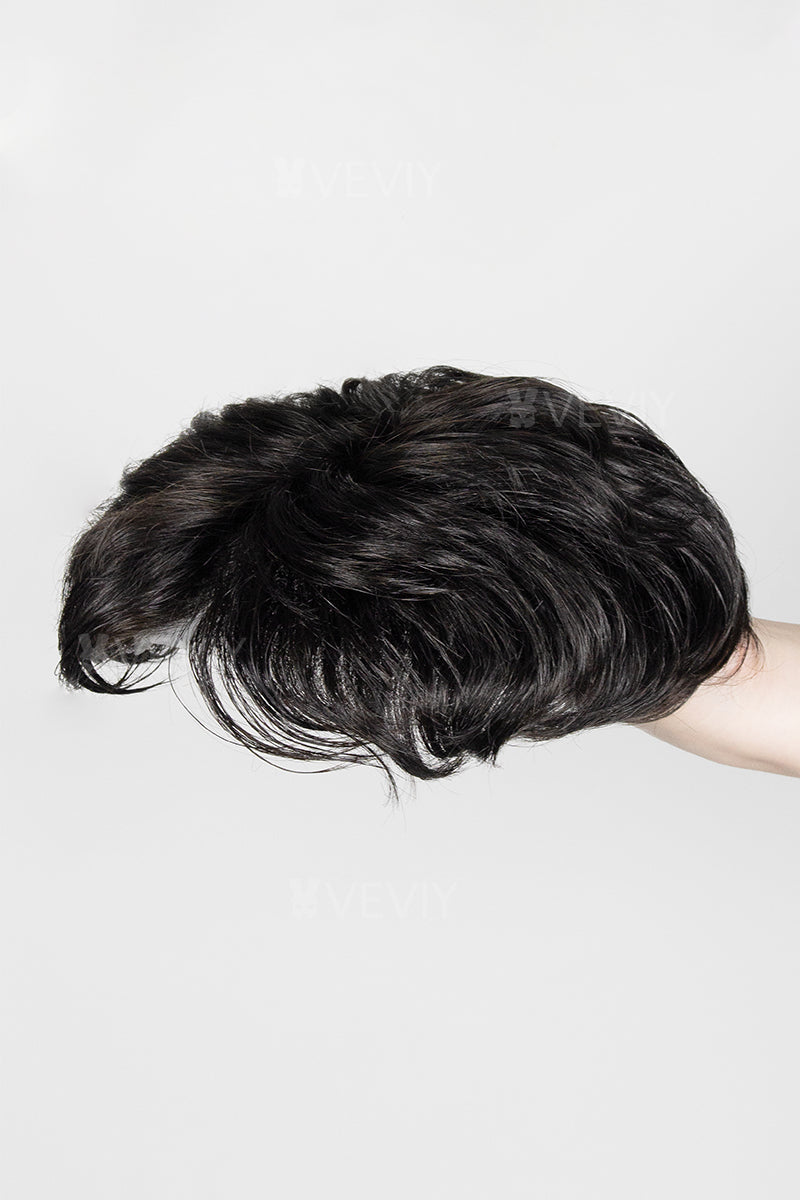 Black hairpiece held by a hand against a white background