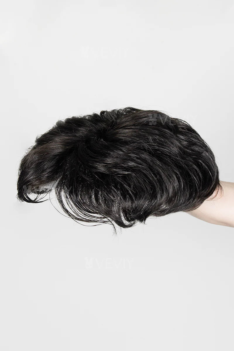 Black hairpiece held by a hand against a white background