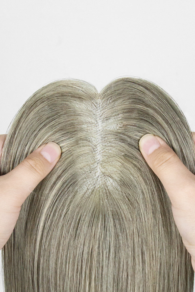 Close-up of a person holding a light brown grey topper with a plain background
